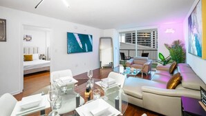 Una sala de estar moderna con comedor, un cuadro grande y vista a un edificio.