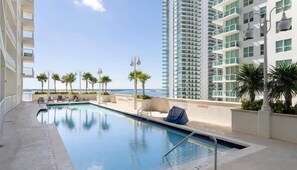 A swimming pool with a view of the ocean, surrounded by palm trees and modern buildings. - Brickell Bay retreat w/ balcony & year-round pool (Miami)