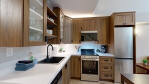 Una cocina moderna con armarios de madera, un refrigerador de acero inoxidable, un horno empotrado y un microondas.