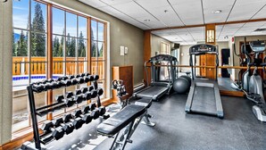 A gym with treadmills, elliptical machines, and dumbbells.