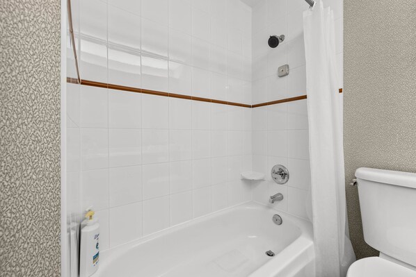 A bathroom with a bathtub, a toilet, and a shower area.