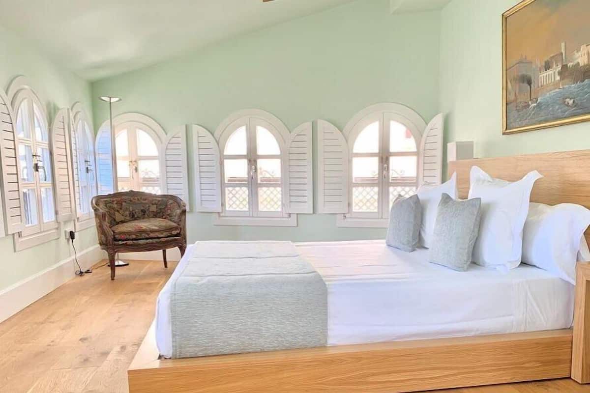 A bedroom with a wooden bed, a chair, and a painting on the wall.