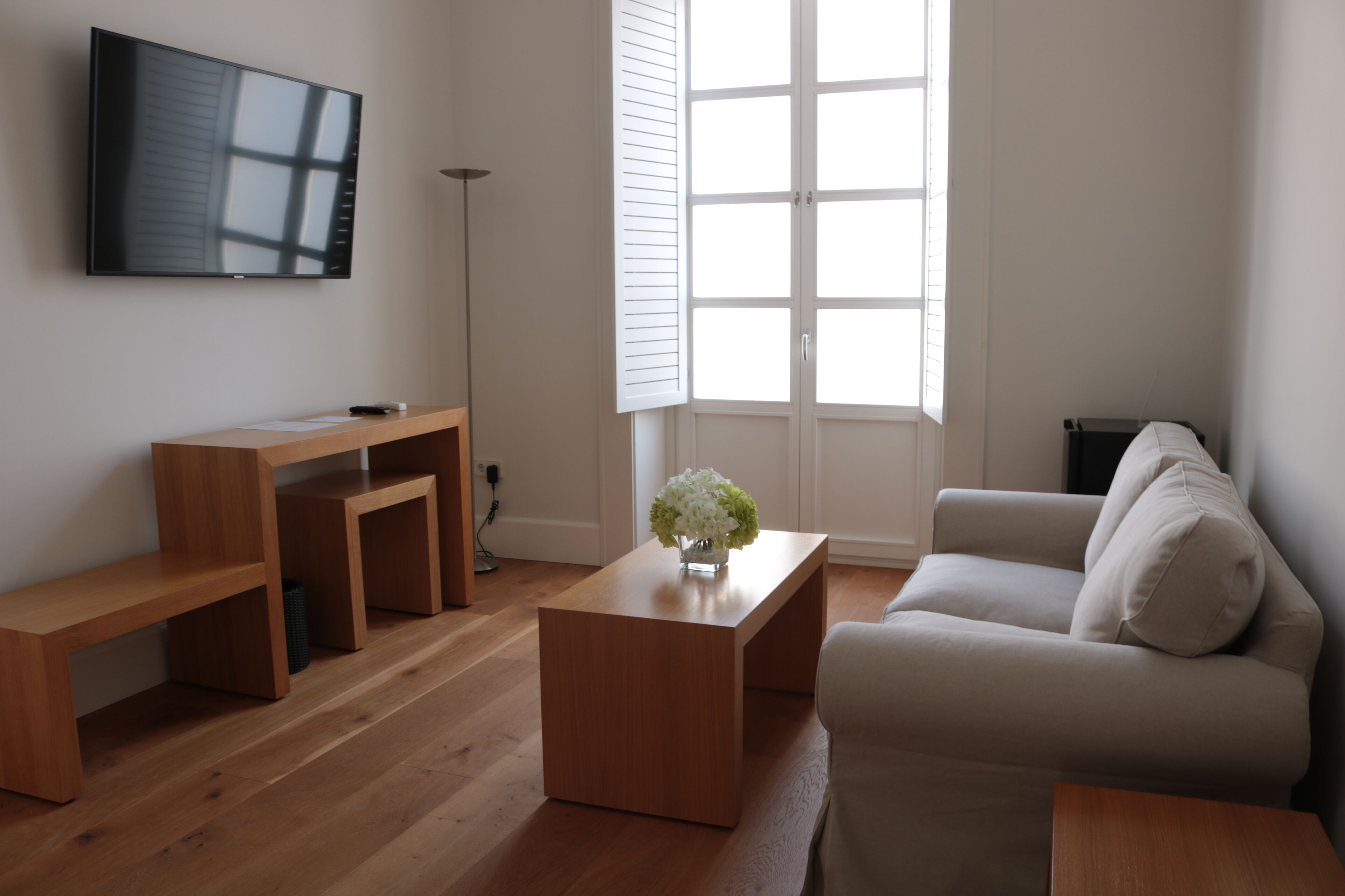 Ein modernes Wohnzimmer mit Flachbildfernseher, Holzmöbeln und einem großen Fenster.