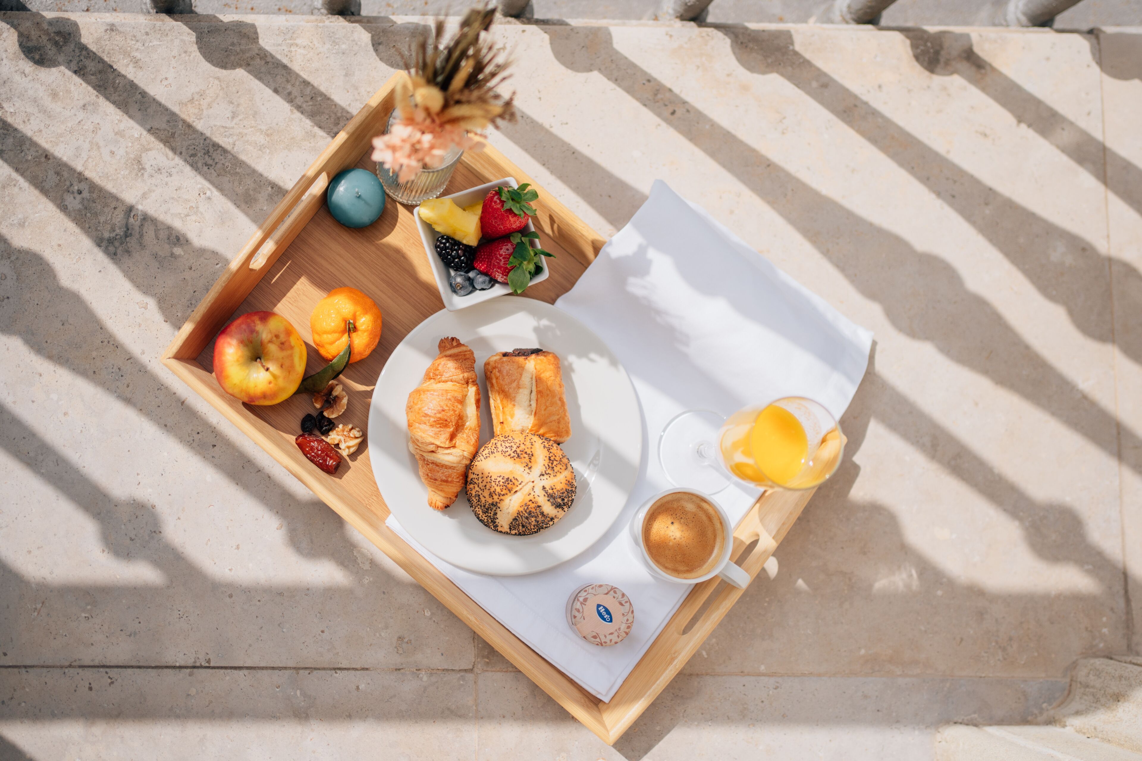 A tray with croissants, a plate of fruit, a glass of orange juice, and a cup of coffee.
