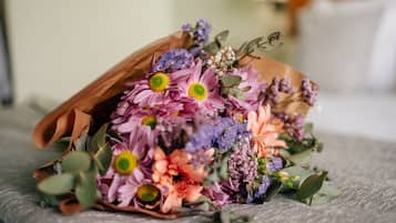 A bouquet of flowers in a brown paper bag on a textured surface.