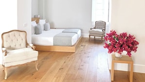 Een slaapkamer met een bed, een stoel, een tafel en een plafondventilator.