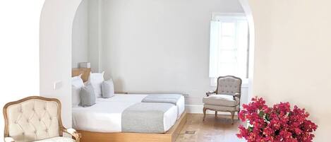 A bedroom with a bed, a chair, a table, and a ceiling fan.