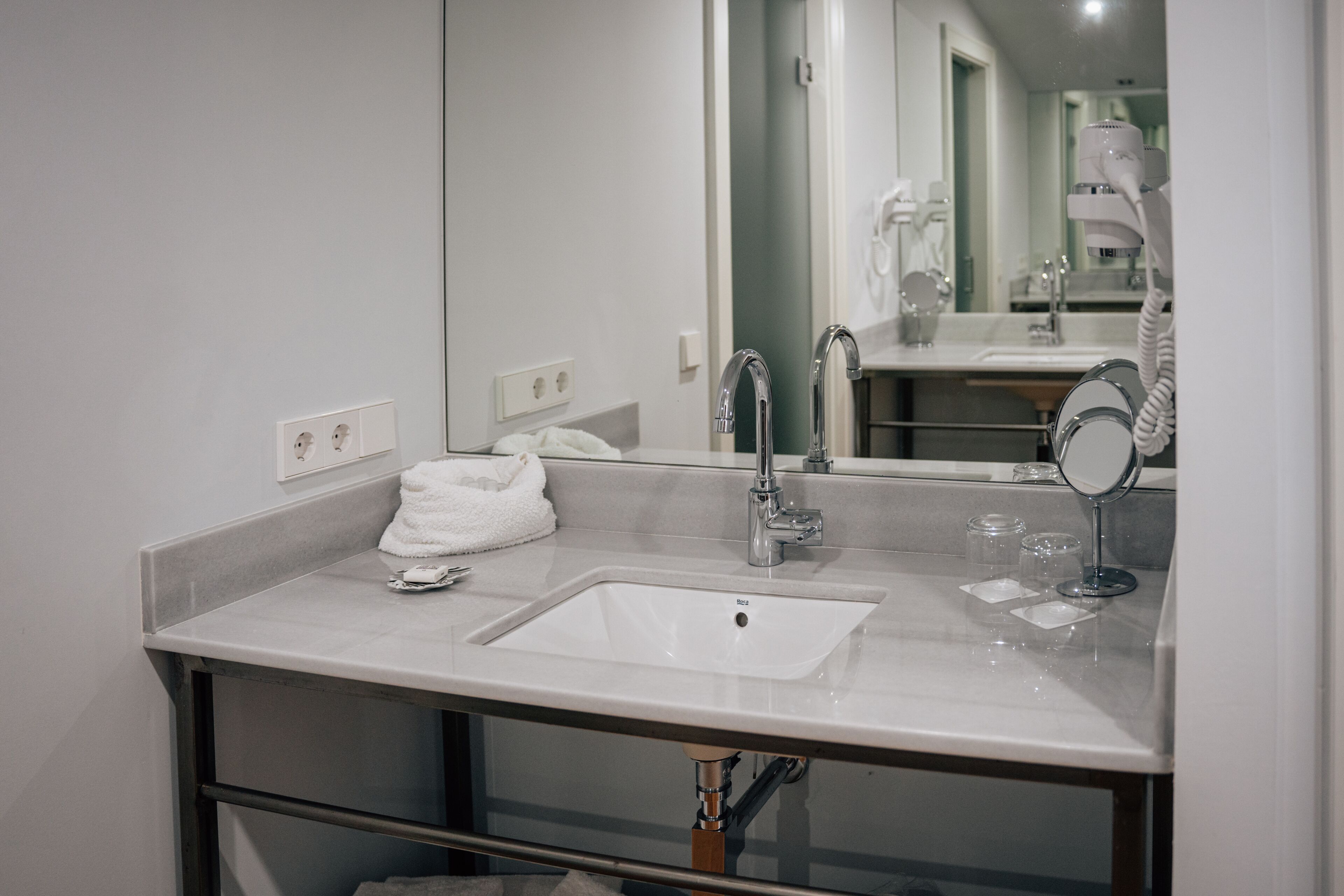 Een moderne badkamer met een grote spiegel, een wastafel en een handdoek.