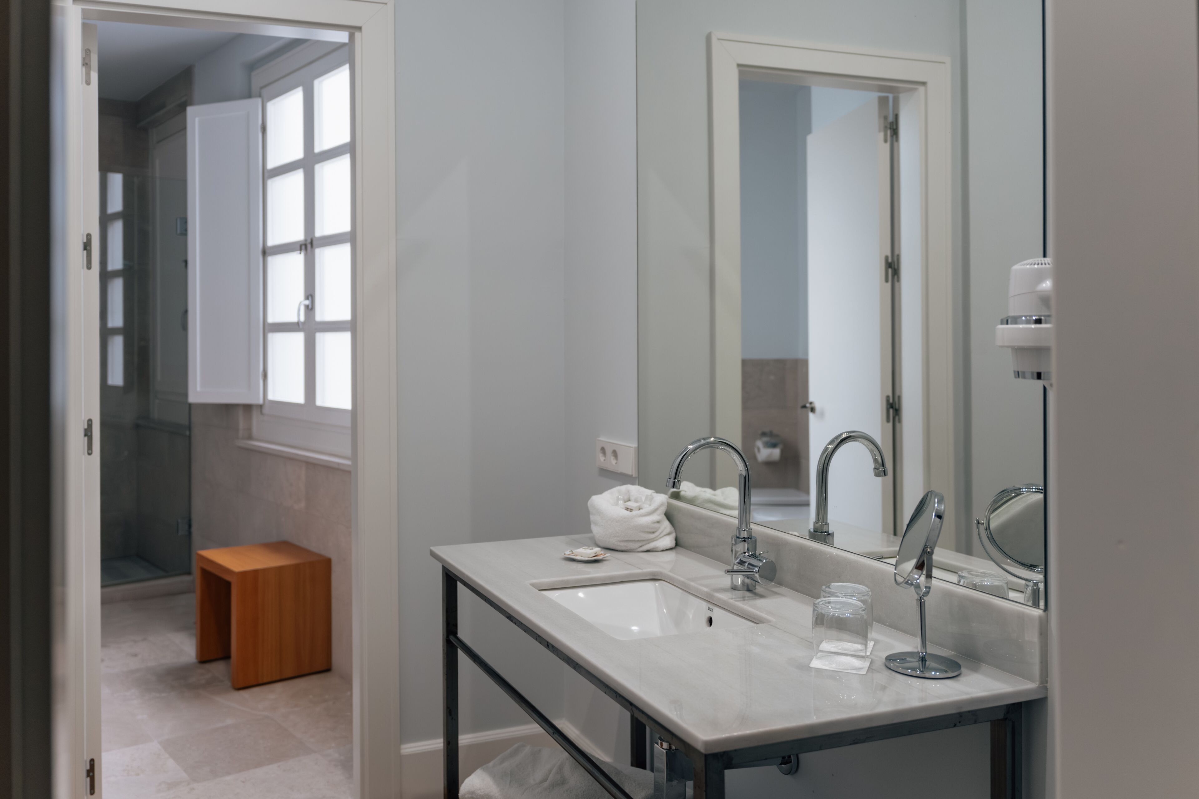 Une salle de bain moderne avec un grand miroir, un lavabo et un espace douche.