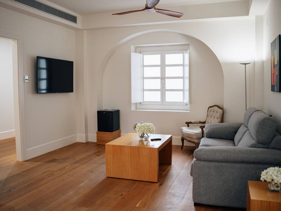 A living room with a wooden coffee table, grey sofa, and a television on the wall.