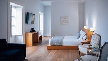 Une chambre moderne comprenant un lit, un bureau, une télévision et un coin salon.