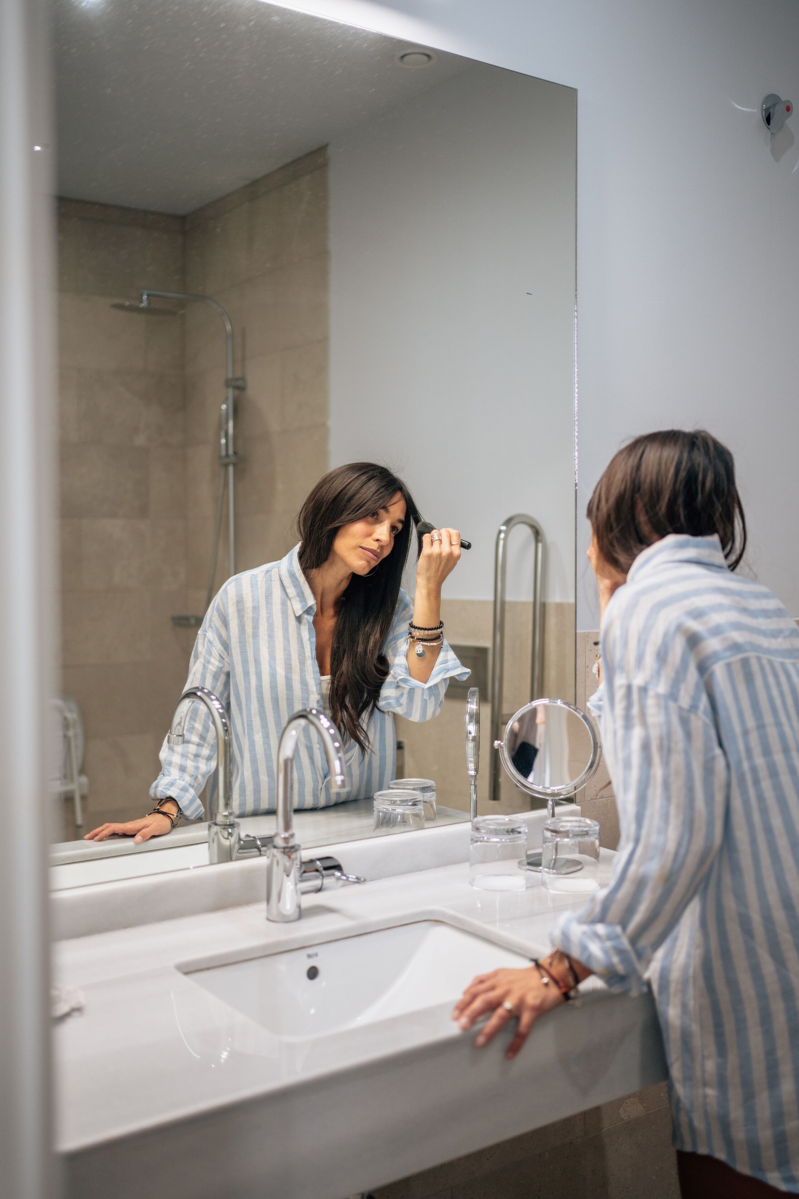 A bathroom with a large mirror, a sink, and a shower.