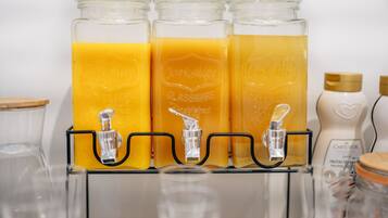 Un distributeur de boissons muni de trois récipients en verre remplis de jus d’orange.