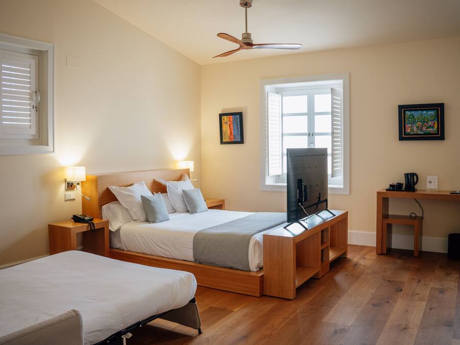 A bedroom with two beds, a TV, a desk, and a ceiling fan.