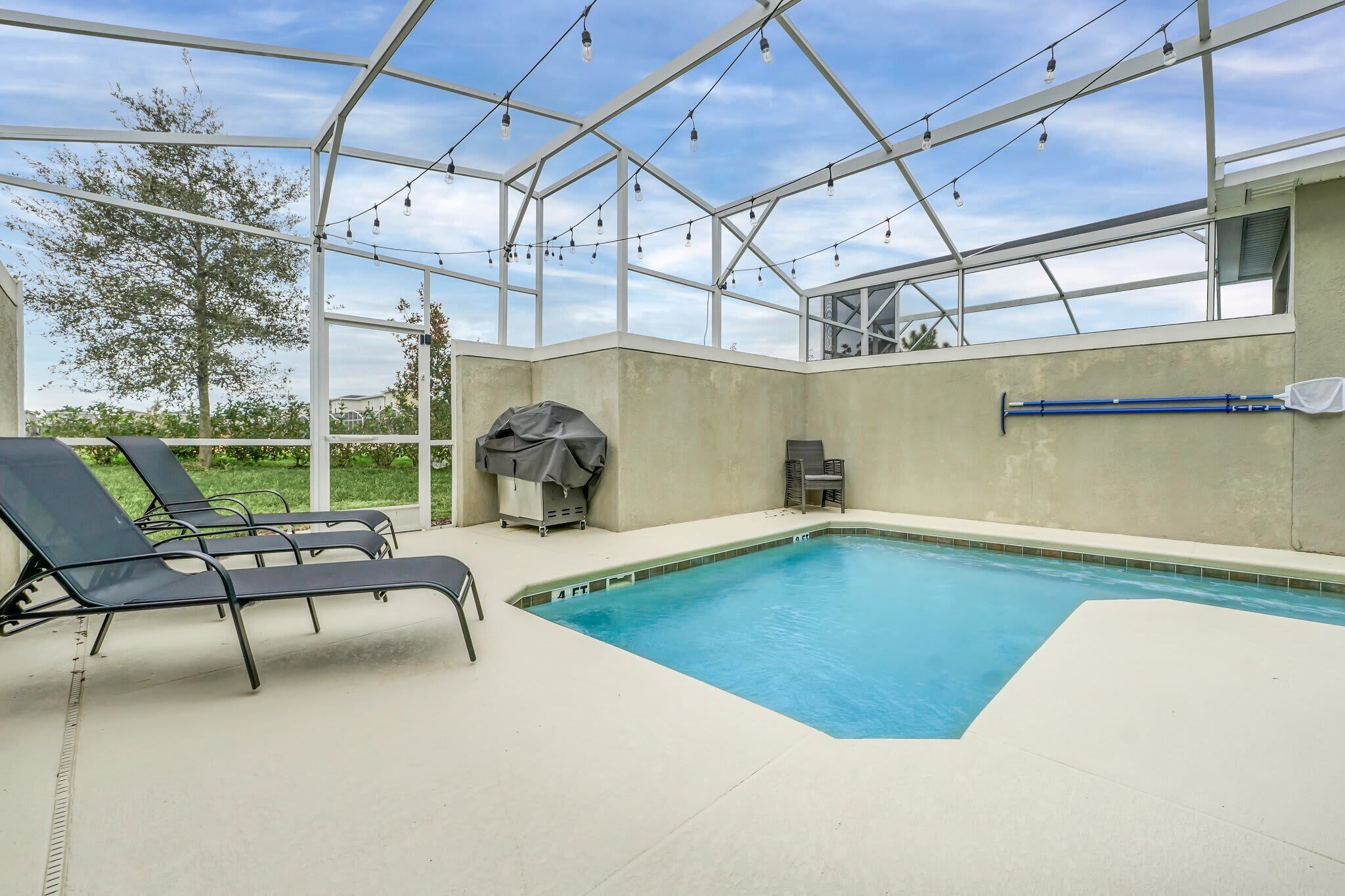 A pool area with lounge chairs and a barbecue grill.
