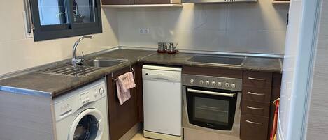 A compact kitchen with a washing machine, dishwasher, oven, and a stovetop.