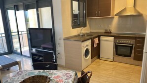 Een compacte keuken met een wasmachine, oven en een eethoek met tafel en mand.