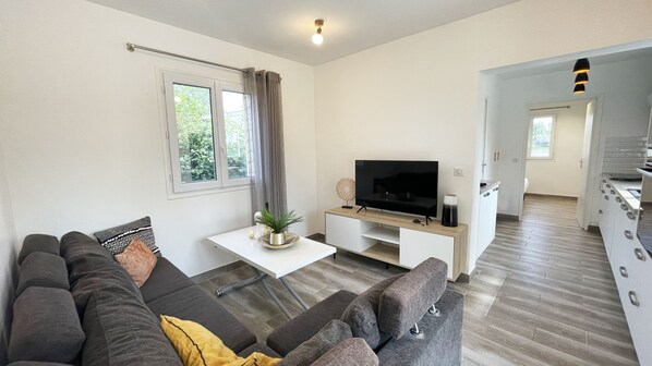 A modern living room with a sofa, TV, and a small table with a plant.