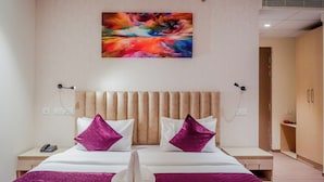 Habitación de hotel con dos camas, un cuadro abstracto grande en la pared y cabecera de madera.