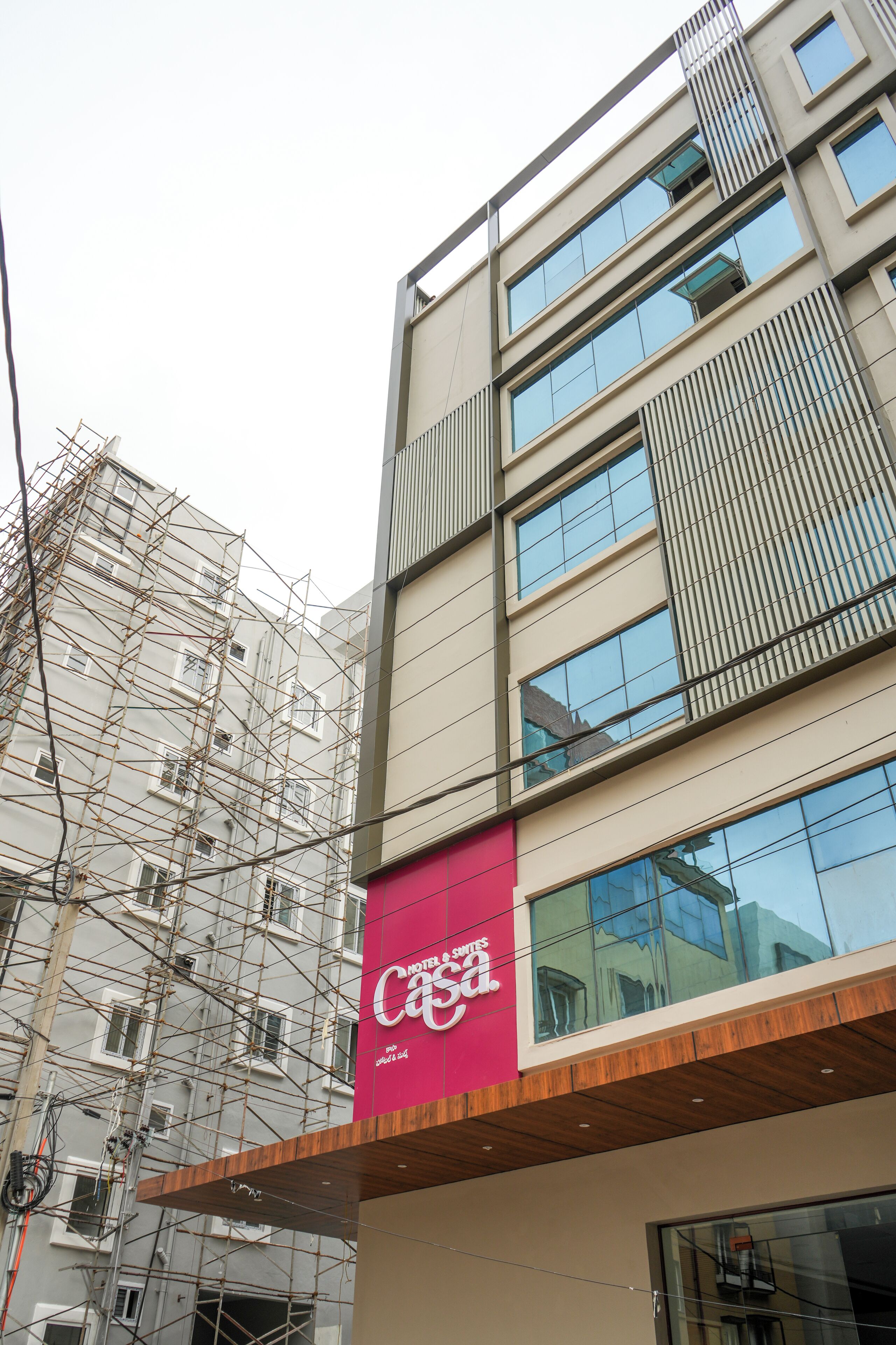 A multi-story building with a prominent pink sign for a hotel.