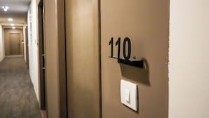 Un pasillo con una puerta marcada con el número 110 y un interruptor de luz en la pared.
