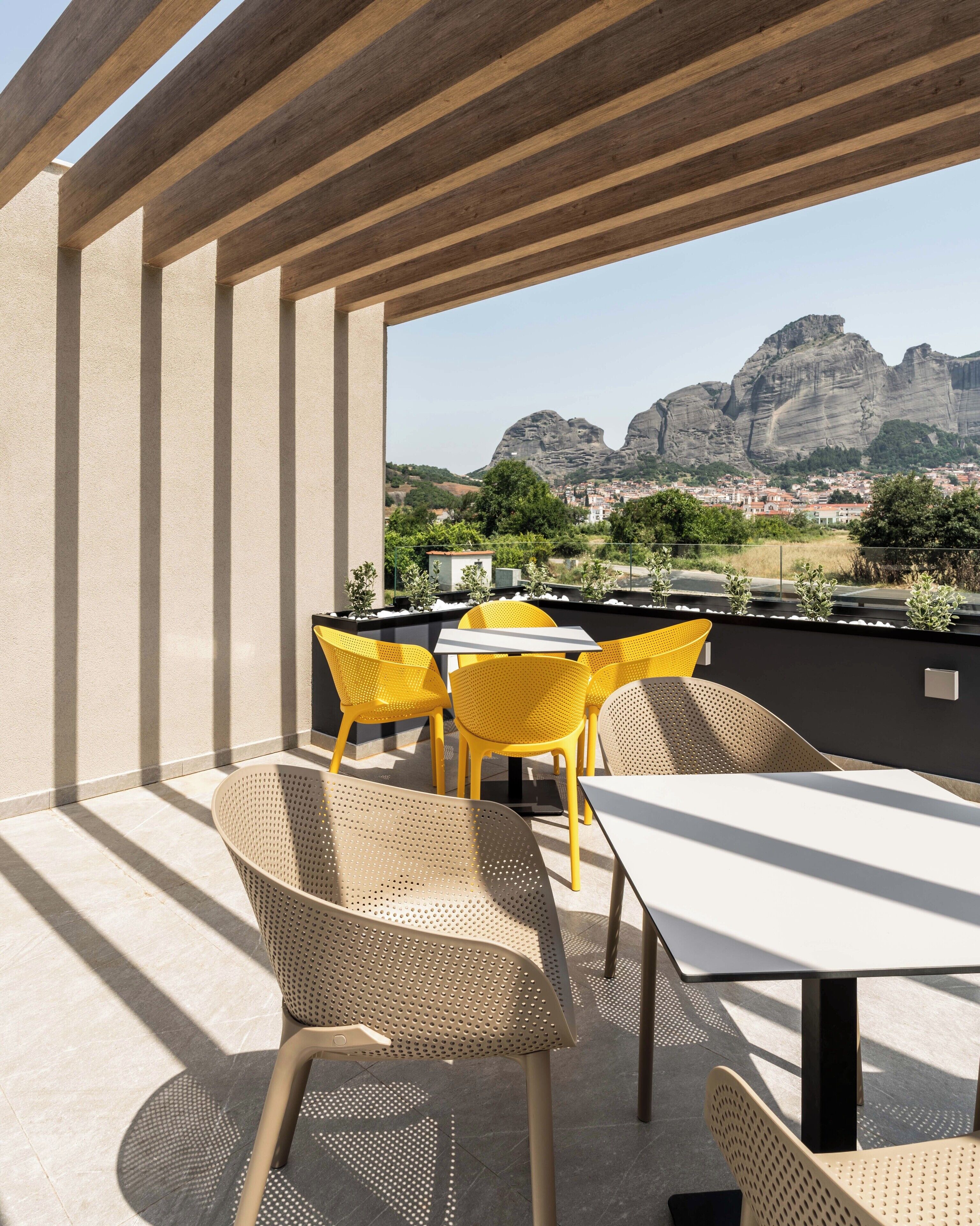An outdoor patio with a table and chairs, a view of mountains, and a cityscape in the background.
