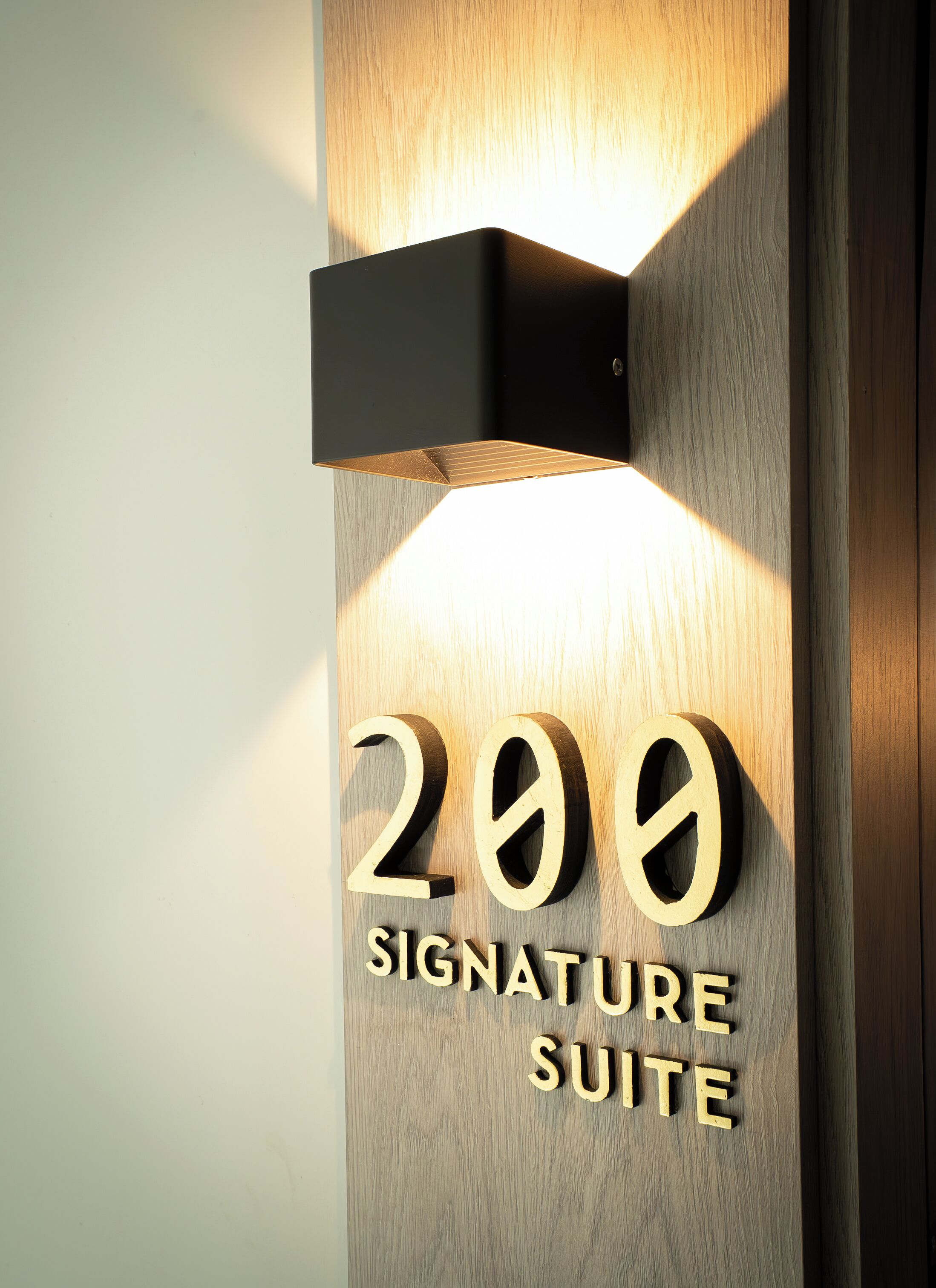 Une porte en bois avec les chiffres « 200 » illuminés et les mots « SIGNATURE SUITE », indiquant une chambre ou une suite particulière.