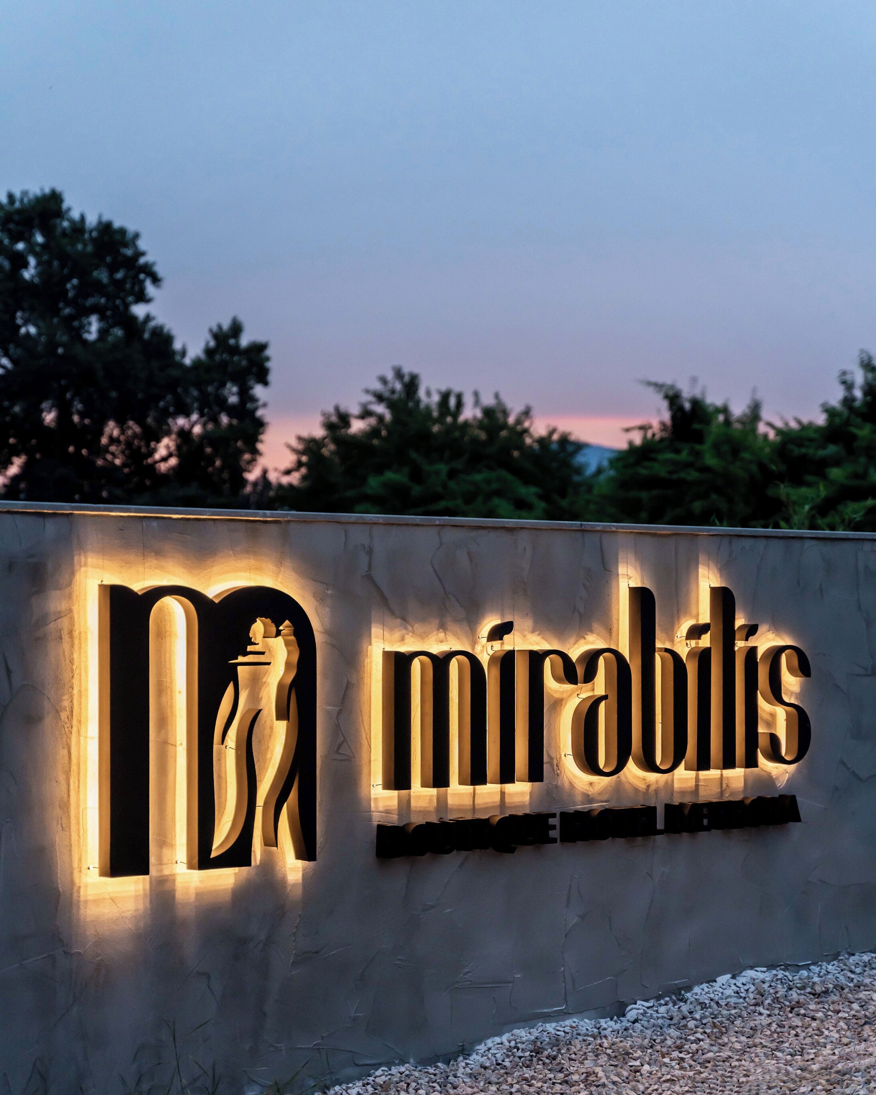 A building with a sign that reads "mirabilis" illuminated in the evening.