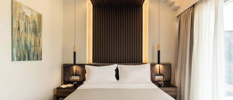Una habitación de hotel moderna con una cama grande, cabecero de listones de madera, mesitas de noche con lámparas y un cuadro en la pared.