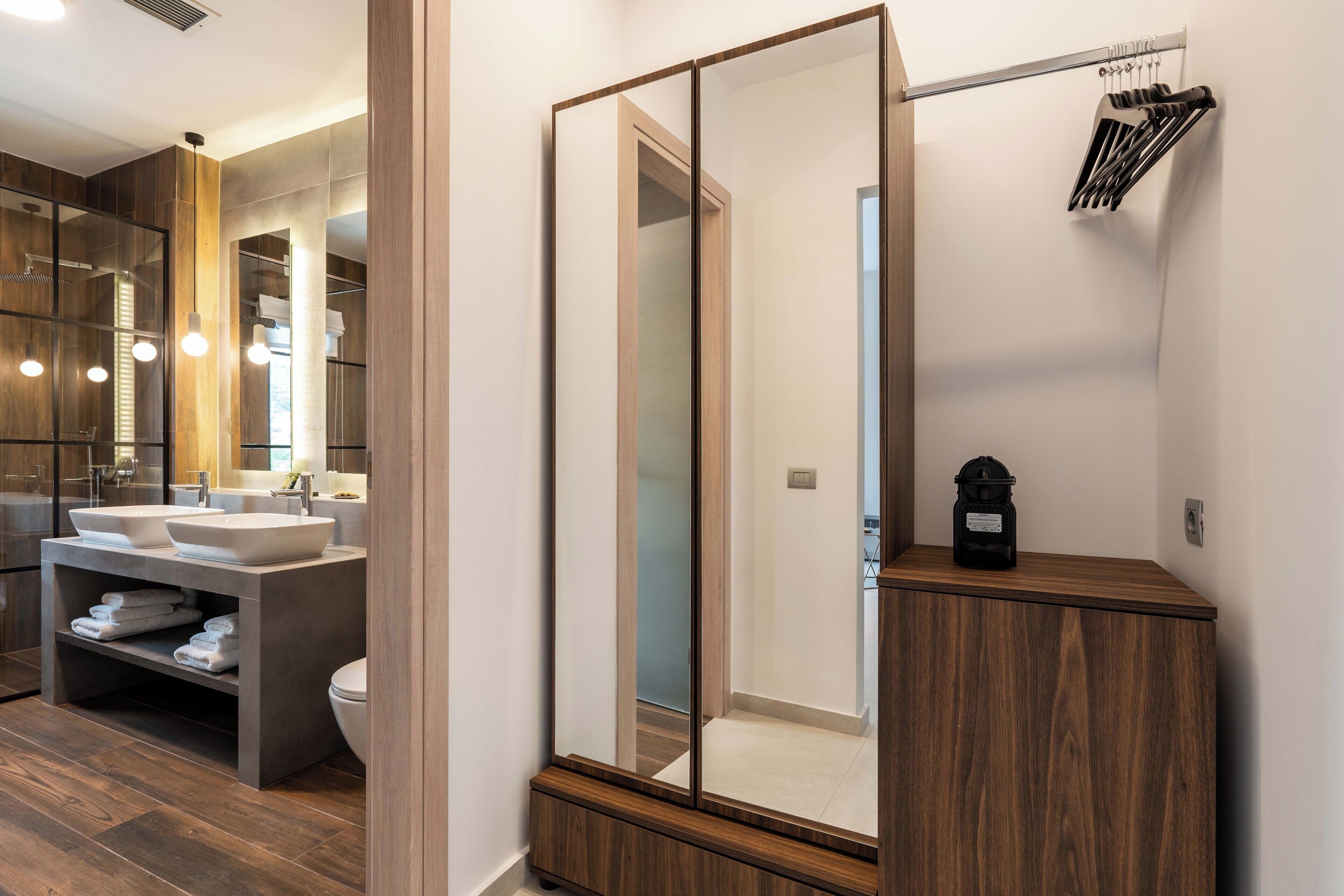 A modern bathroom with a large mirror, wooden vanity, and a built-in sink.