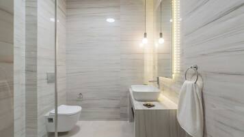 Ein modernes Badezimmer mit Duschkabine aus Glas, Toilette, Waschbecken mit Spiegel und einem Handtuch an der Wand.