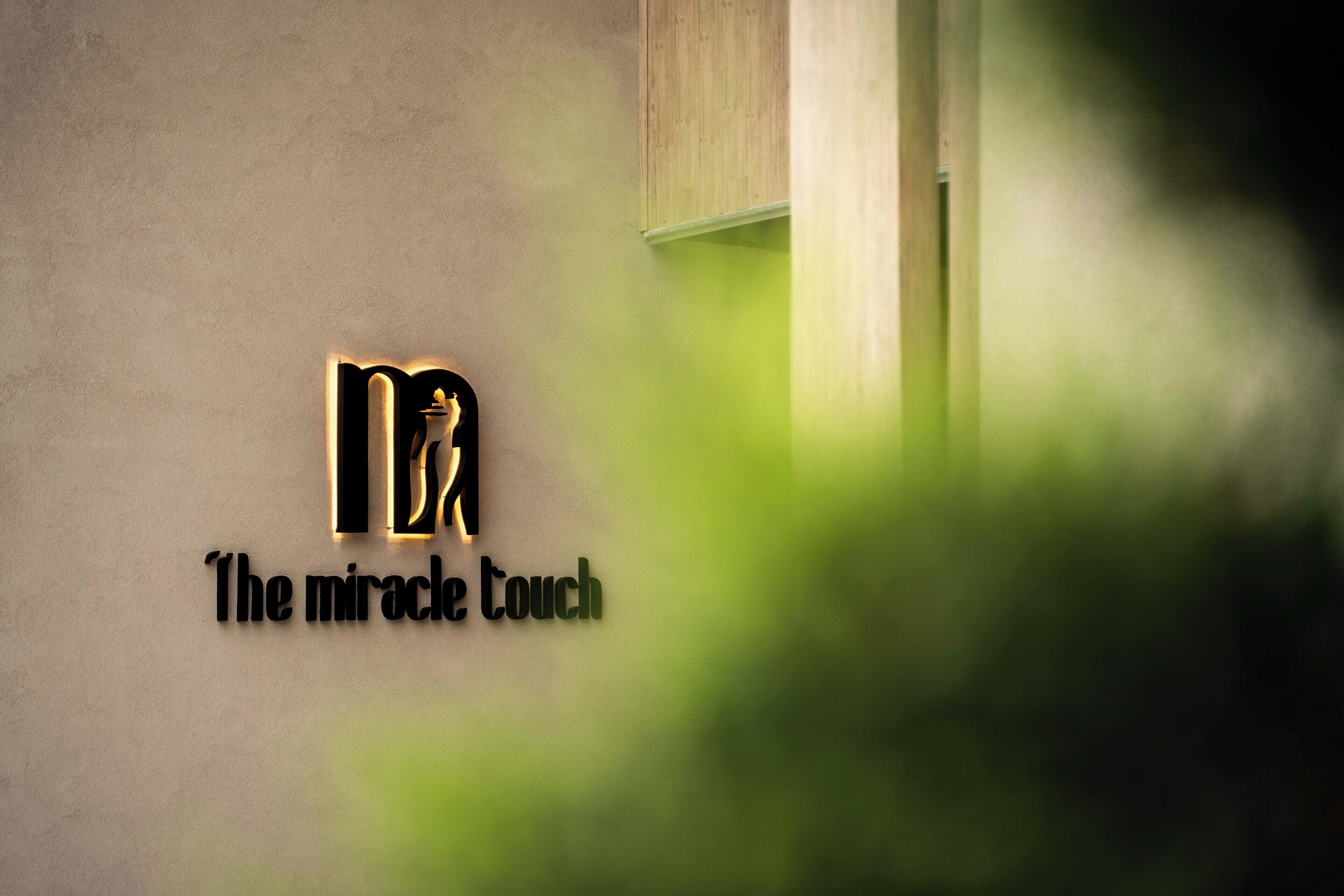 Ein Logo mit dem Text „The miracle touch“ an einer Wand.