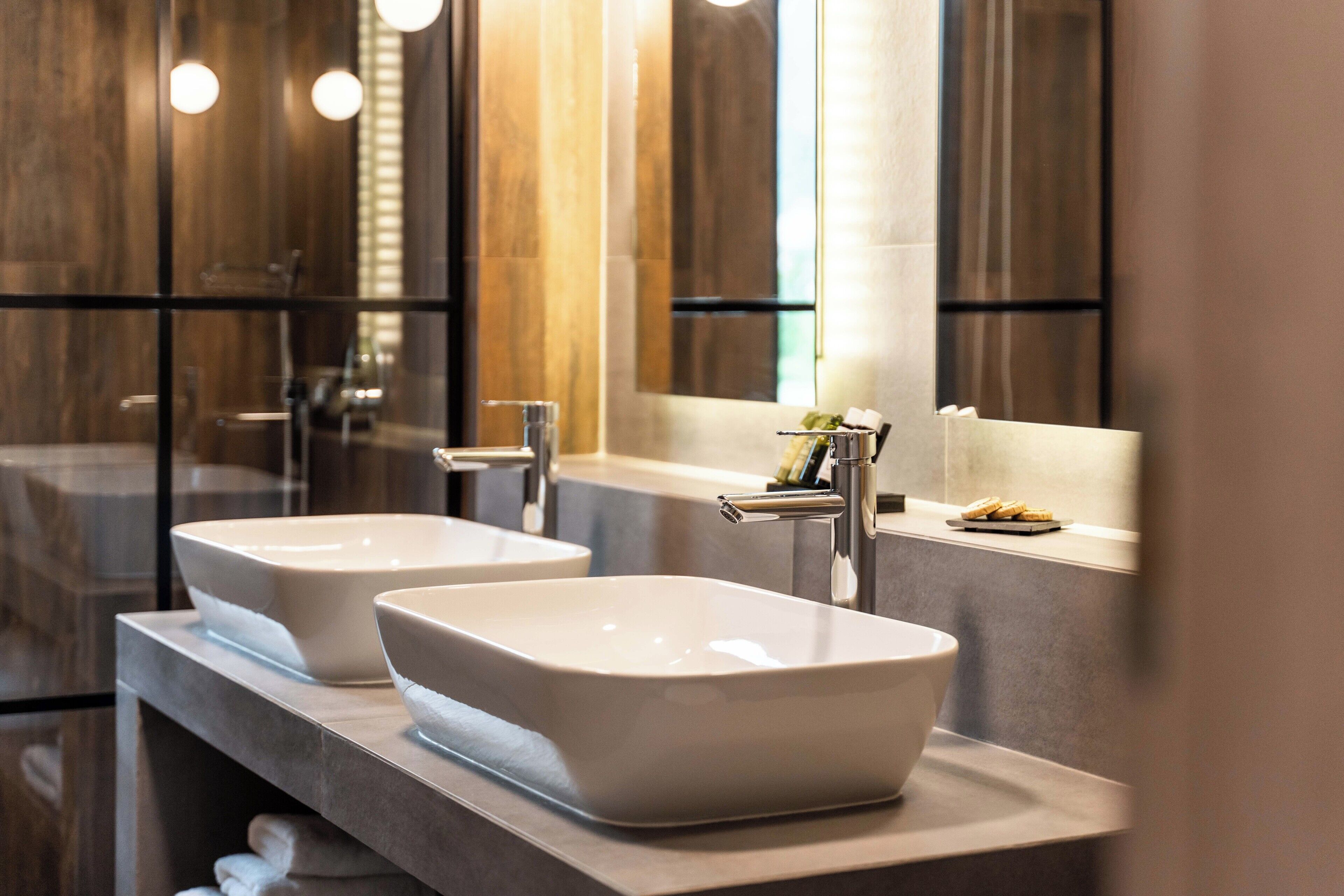 A modern bathroom with two large, white, rectangular sinks and a large mirror above them.