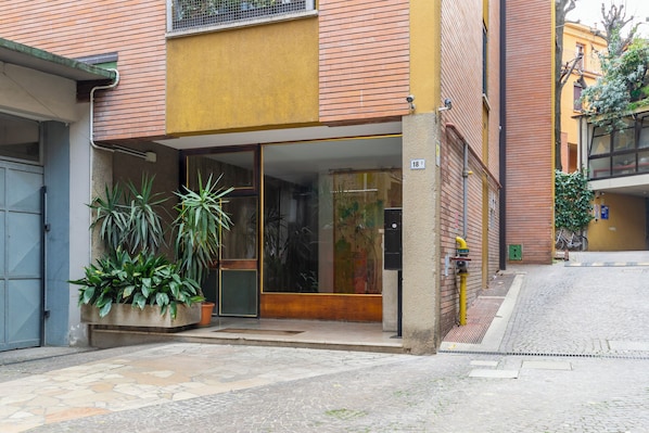 A building with a glass entrance, potted plants, and a number '18' sign.