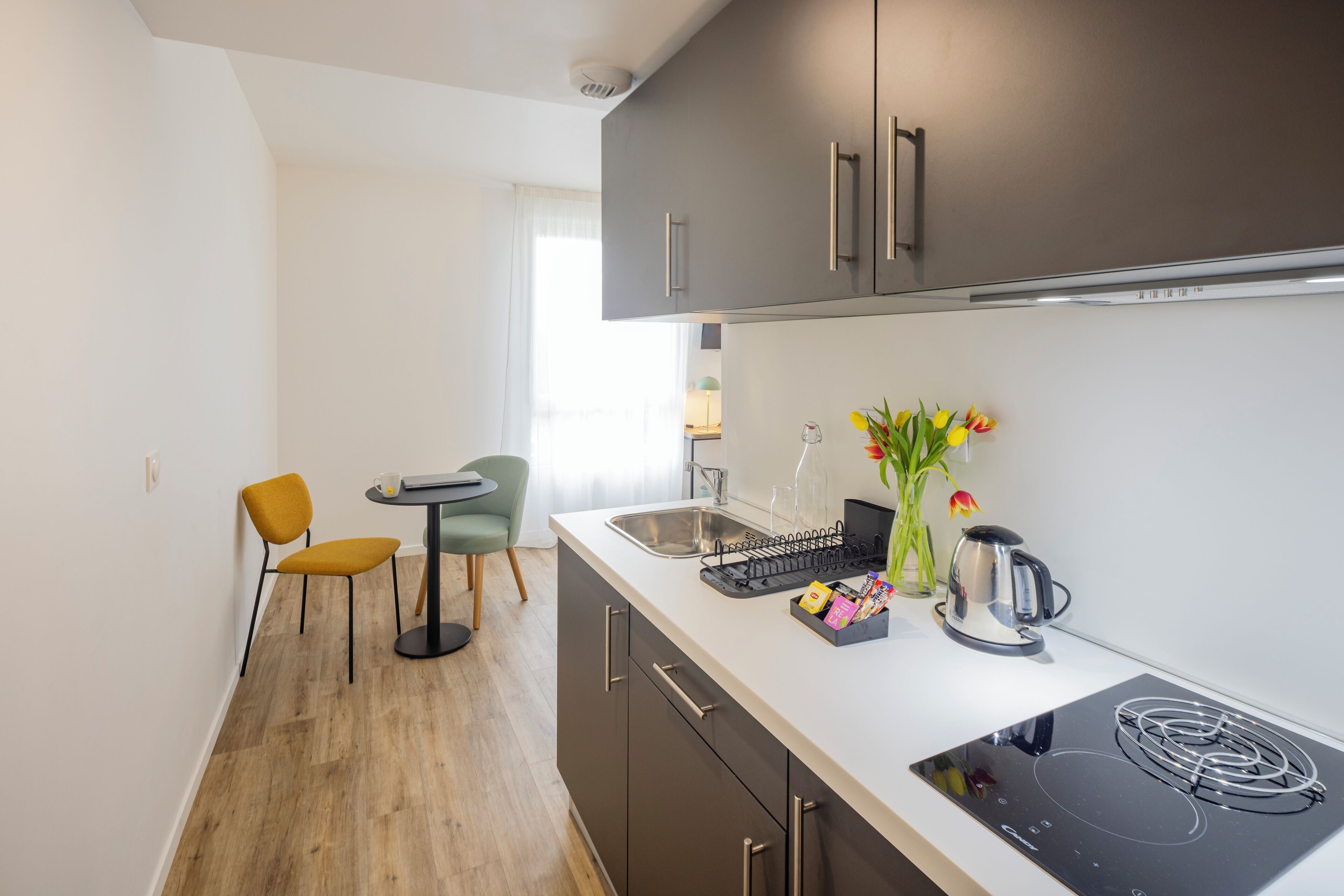 A modern kitchen with a built-in stove, a sink, and a dining area with a table and chairs.