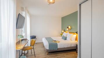 Une chambre d’hôtel équipée d’un lit, d’un bureau, d’une chaise, d’une télévision et d’une armoire.