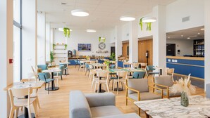 A spacious hotel lobby with multiple seating areas, including sofas and tables, and a reception desk. - All Suites Appart Hôtel | Le Havre Centre - Les docks (Le Havre)