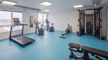 A gym with treadmills, elliptical machines, a bench press, and a squat rack.