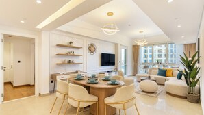 A modern living room with a sofa, coffee table, and a dining area with chairs and a table set for four. - Marina Residences 2 501 (Dubai)