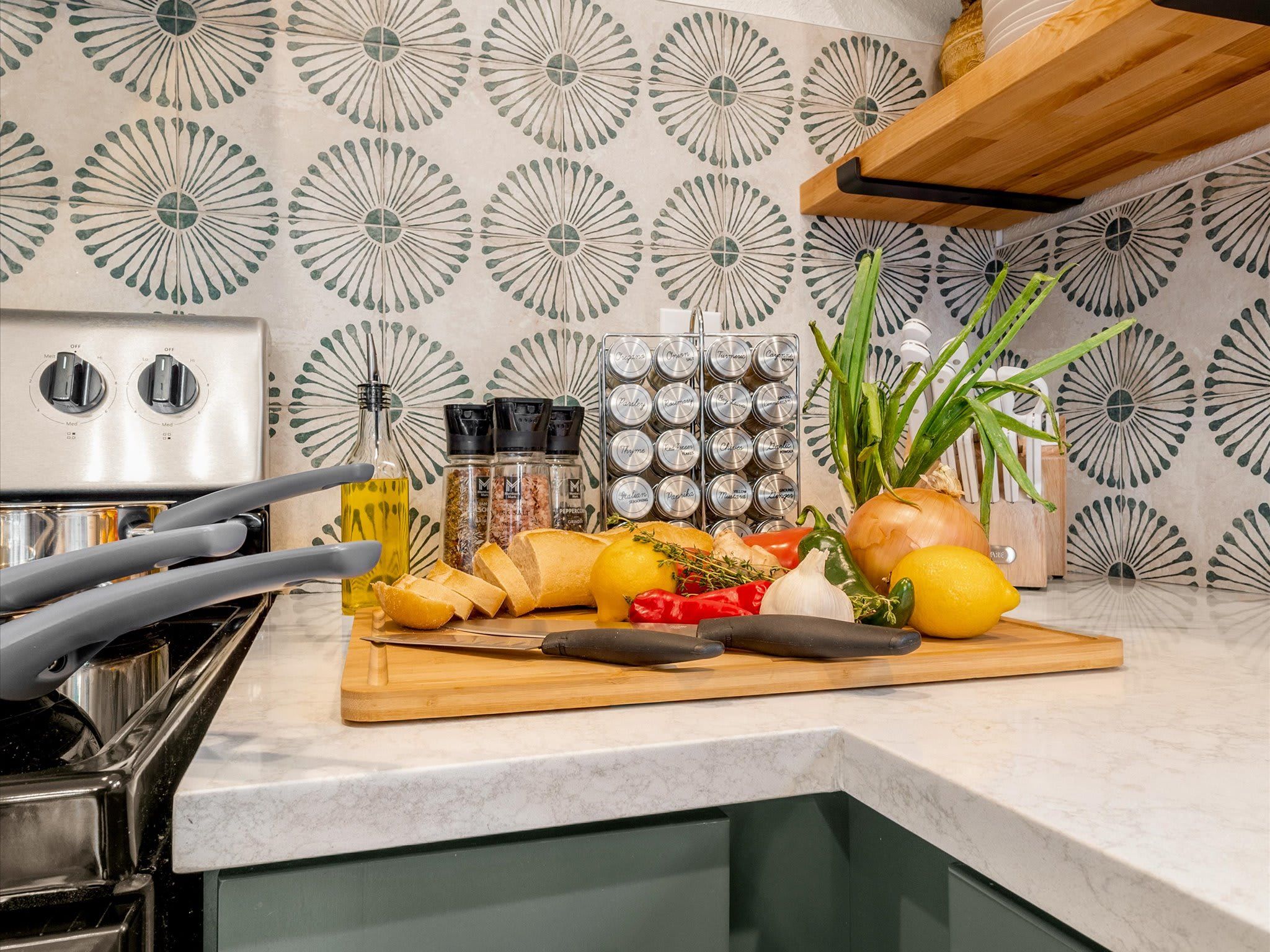A kitchen counter with a cutting board, various vegetables, a bottle of oil, and a spice rack.