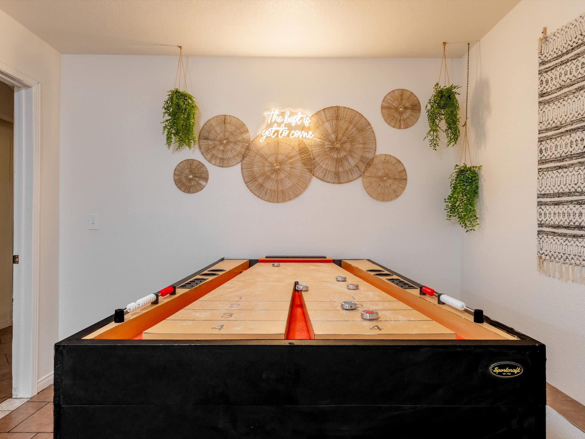 A foosball table in a room with a wall-mounted decorative item and a woven tapestry.
