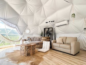 A tented room with a sofa, a coffee table, and a hanging plant.