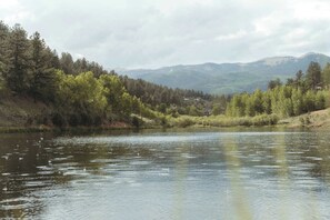A calm river with trees and mountains in the background. - Theater Dome | Stargazing Hot Tub Hammock Terrace (Bailey)