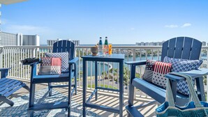 Ein Balkon mit zwei Adirondack-Stühlen, einem kleinen Tisch und Blick auf eine Brücke sowie eine Skyline.