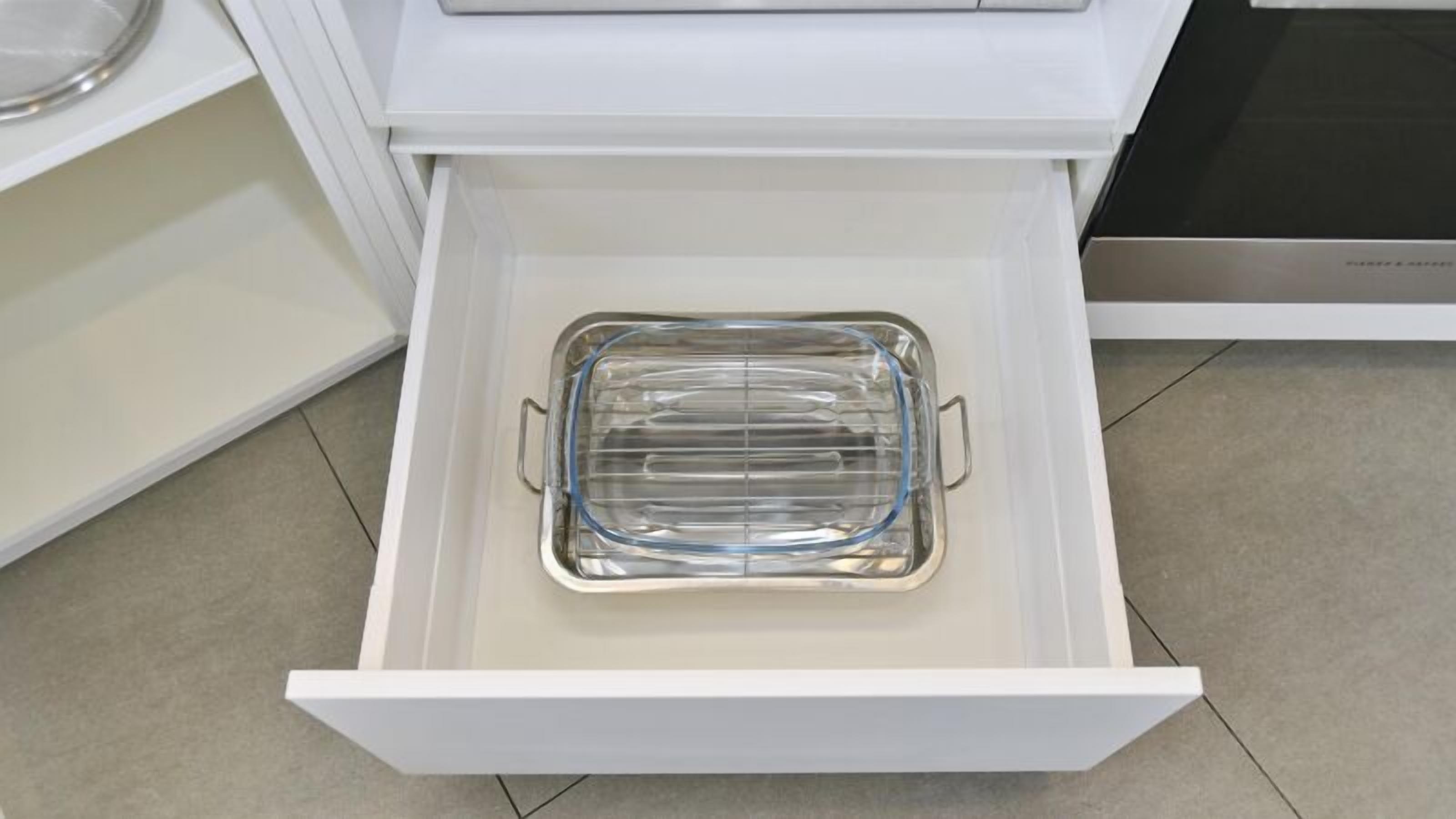 Un tiroir de cuisine contenant un plat de cuisson en verre transparent.