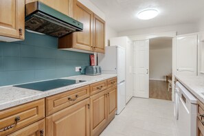 Una cocina con armarios de madera, un refrigerador blanco, un microondas y un lavamanos.