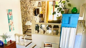 A cozy interior with a stone wall, a blue cabinet, a dining table with chairs, and a staircase. - La Maison Près de la Fontaine (Talairan)