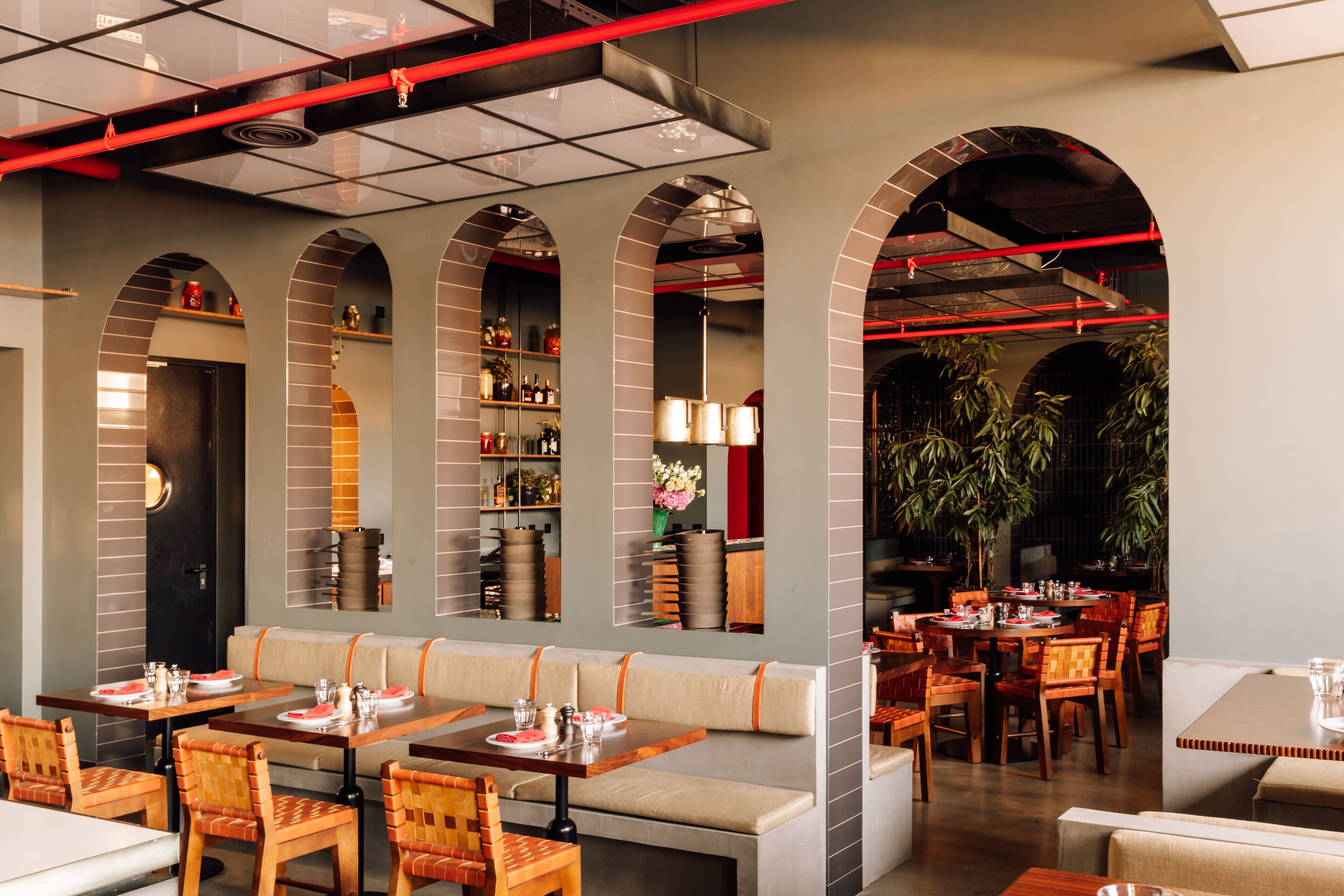 A restaurant with multiple seating areas, including booths and tables, and a variety of plants and decorative items.