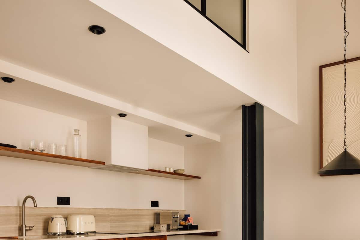 A modern kitchen with a high ceiling, built-in cabinets, and a dining area with a table and chairs.