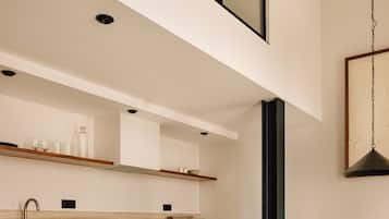 A modern kitchen with a high ceiling, built-in cabinets, and a dining area with a table and chairs.